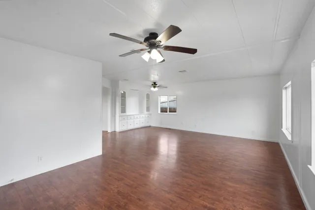 a view of an empty room with window and wooden floor