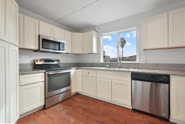 a kitchen with stainless steel appliances granite countertop a stove a sink and a microwave