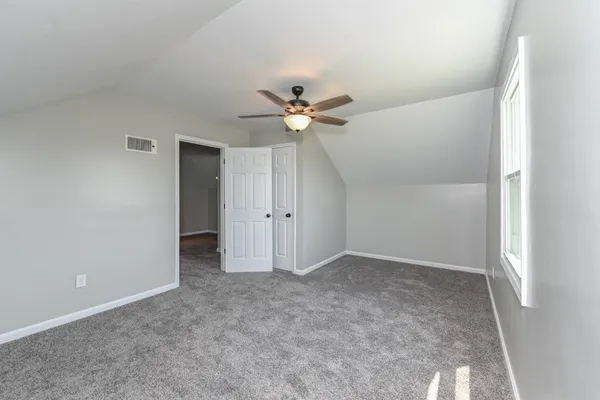 an empty room with ceiling fan and window