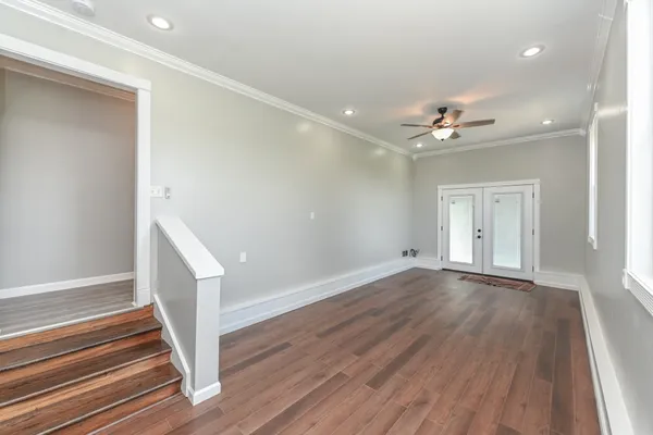 a view of an empty room with wooden floor and a window