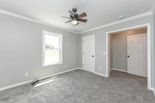 a view of a livingroom with a ceiling fan & windows