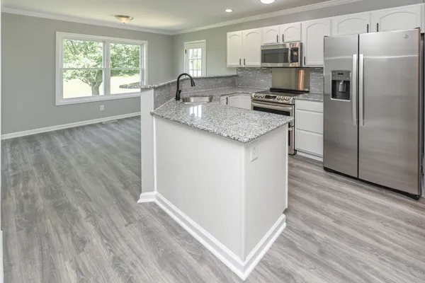 a kitchen with stainless steel appliances granite countertop a refrigerator and a stove top oven