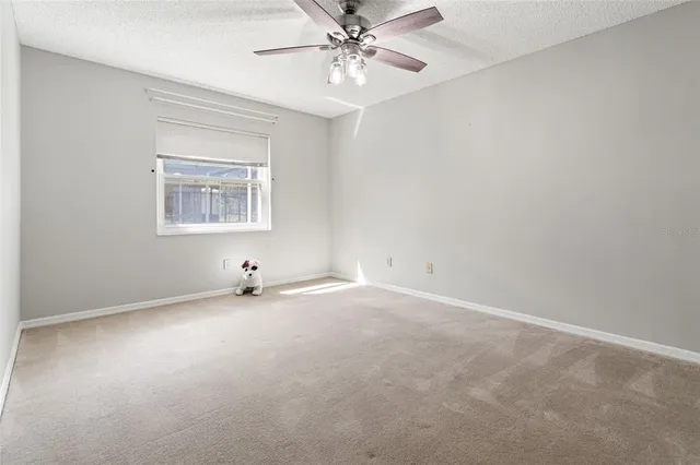an empty room with windows and ceiling fan