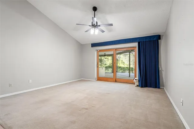 an empty room with a chandelier fan and windows