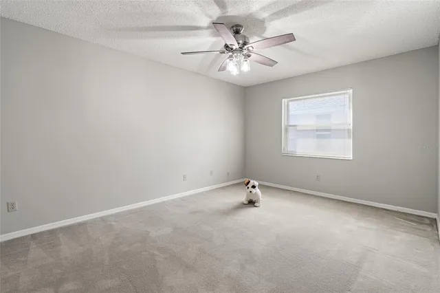 an empty room with a window and a ceiling fan