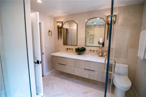 a bathroom with double vanity sink a toilet a mirror and shower