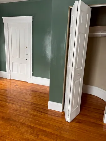 an empty room with wooden floor and entrance