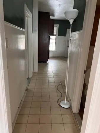 a view of a refrigerator in kitchen and an empty room