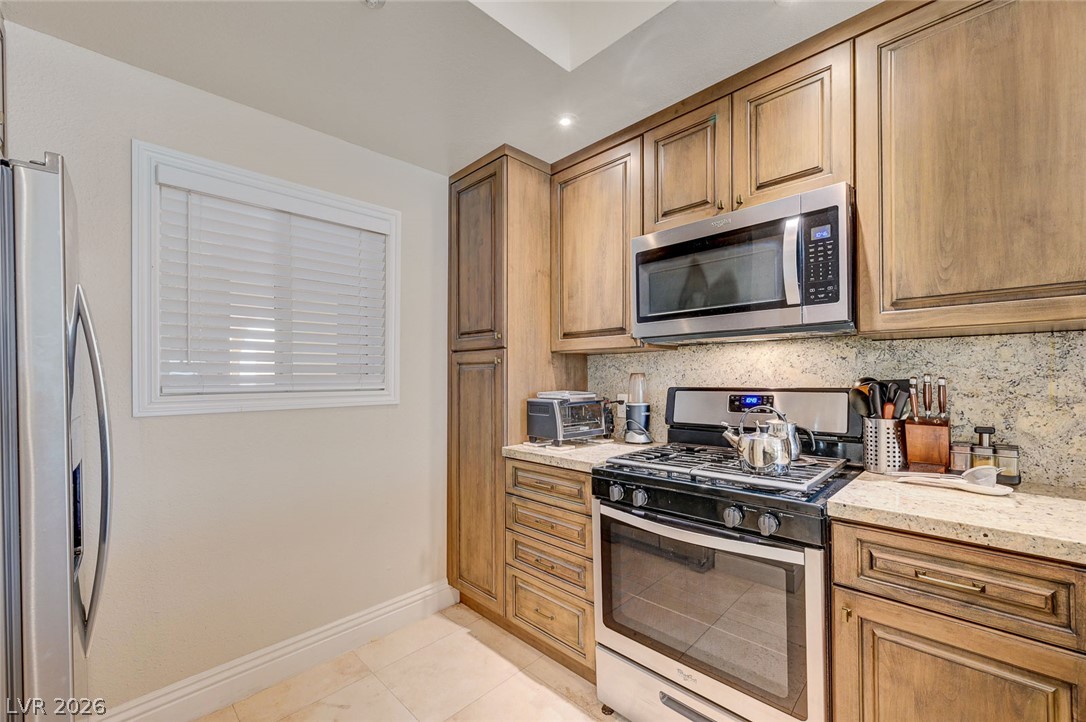 230 East Flamingo Road, Unit 106 Las Vegas, NV 89169 - Photo 10 of 66 Well-appointed culinary space featuring sleek appliances and warm wooden cabinetry.
