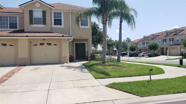 a view of a house with a yard and palm trees