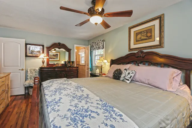 a bedroom with a bed and a dresser with wooden floor