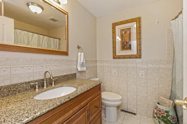 a bathroom with a granite countertop toilet sink and mirror