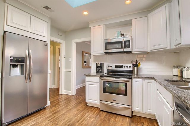 a kitchen with stainless steel appliances granite countertop a stove a refrigerator and a sink