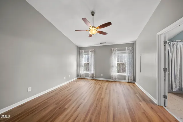 a view of an empty room with a window and wooden floor
