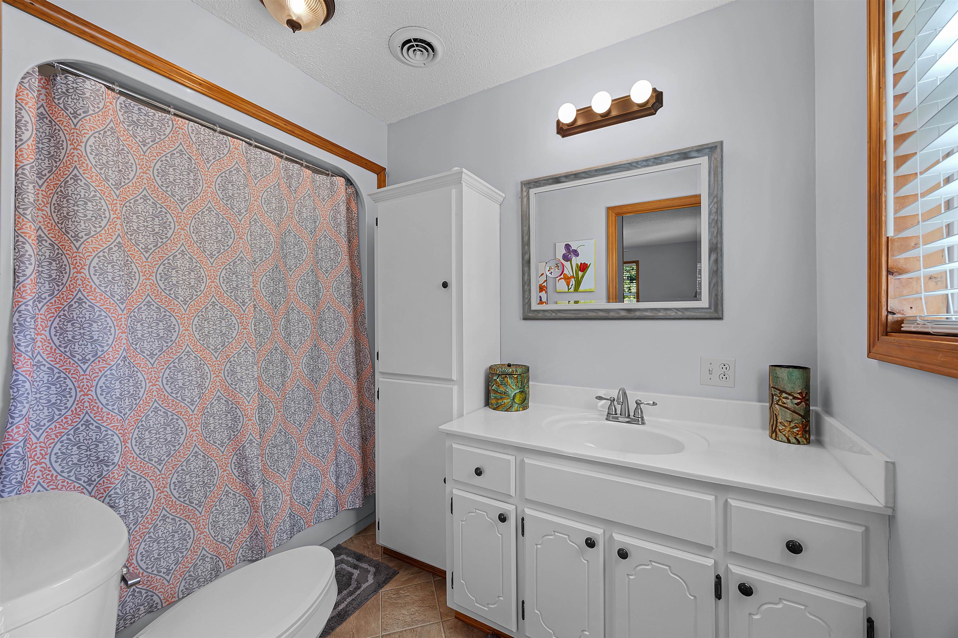 61 Cr 303 Road Iuka, MS 38852 - Photo 16 of 19 Bathroom with toilet, tile patterned flooring, curtained shower, vanity, and a textured ceiling