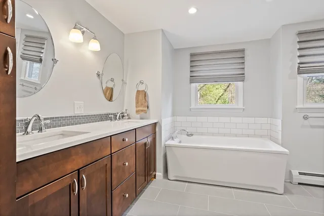 a bathroom with a sink double vanity granite tub and a mirror