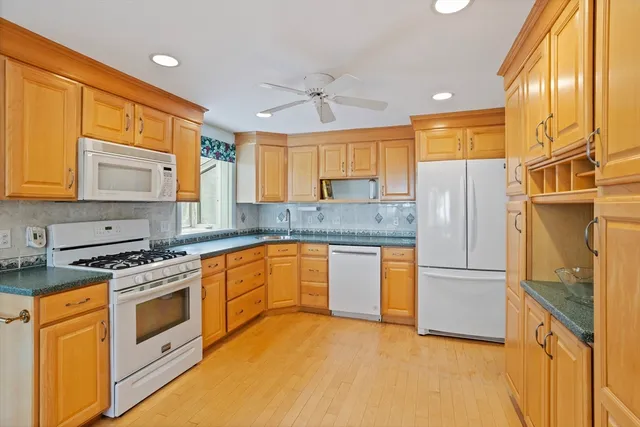 a kitchen with stainless steel appliances granite countertop a refrigerator a stove and a sink with wooden floor