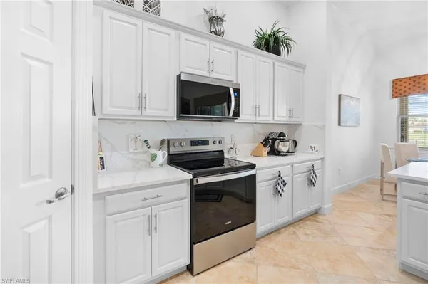 a kitchen with kitchen island a white counter top space cabinets and stainless steel appliances