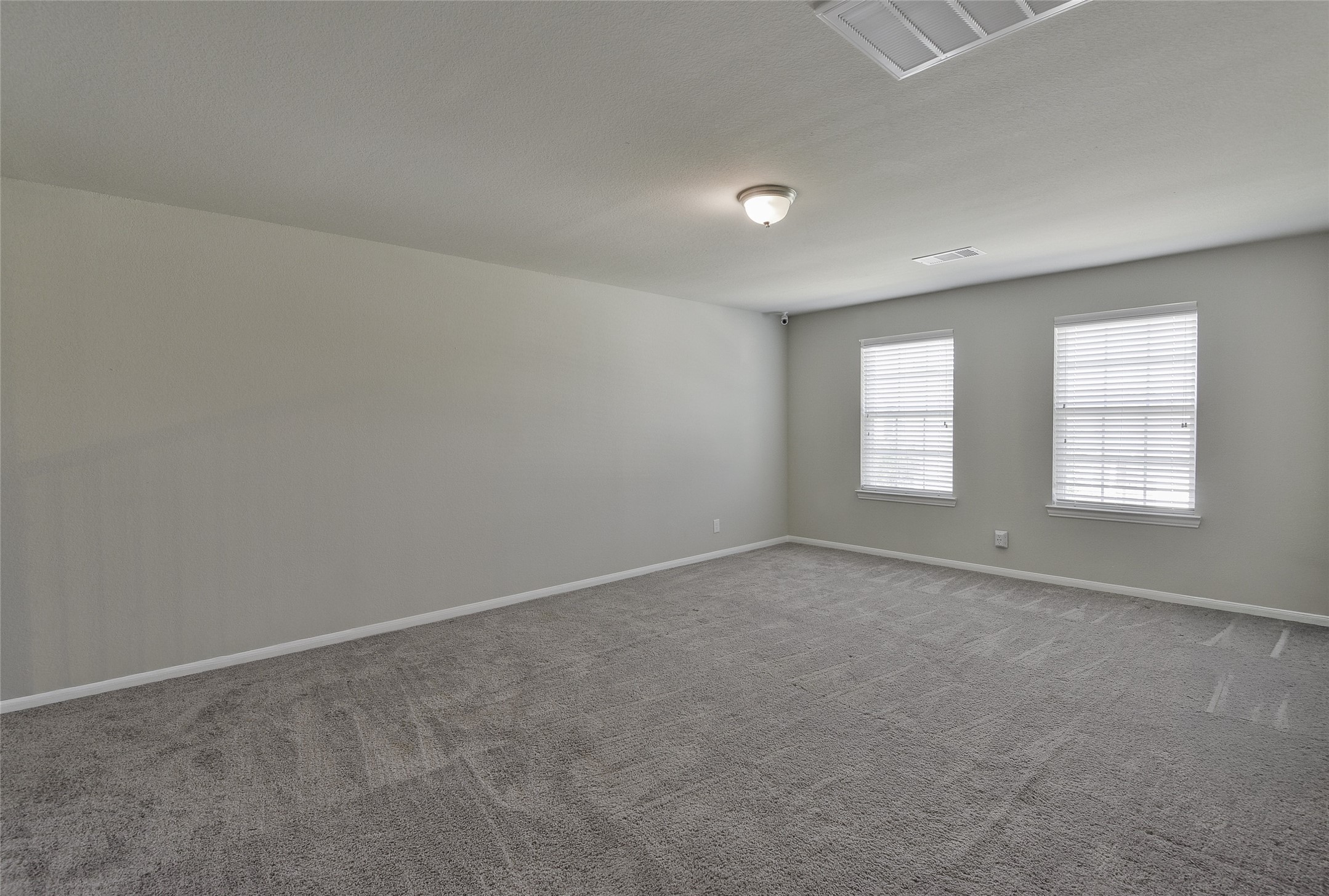 614 Pequin Road Crosby, TX 77532 - Photo 24 of 43 This spacious family room features neutral carpeting, light gray walls, and ample natural light from two windows.