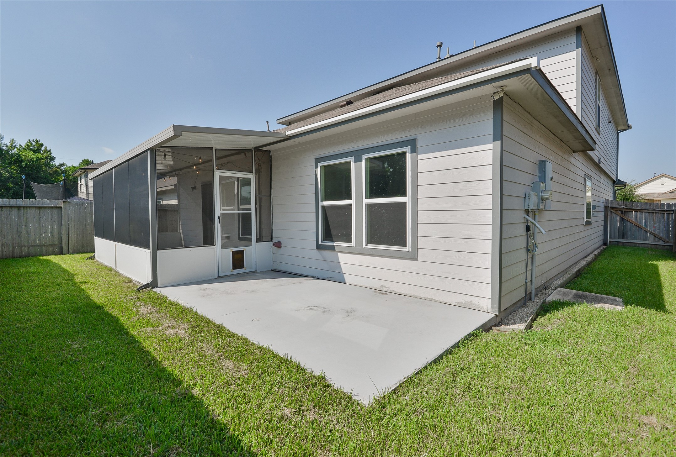 614 Pequin Road Crosby, TX 77532 - Photo 42 of 43 This photo showcases the backyard of a home, featuring a screened-in patio and additional patio space. The yard is fenced for privacy with a grass lawn. Perfect for outdoor relaxation and entertainment.