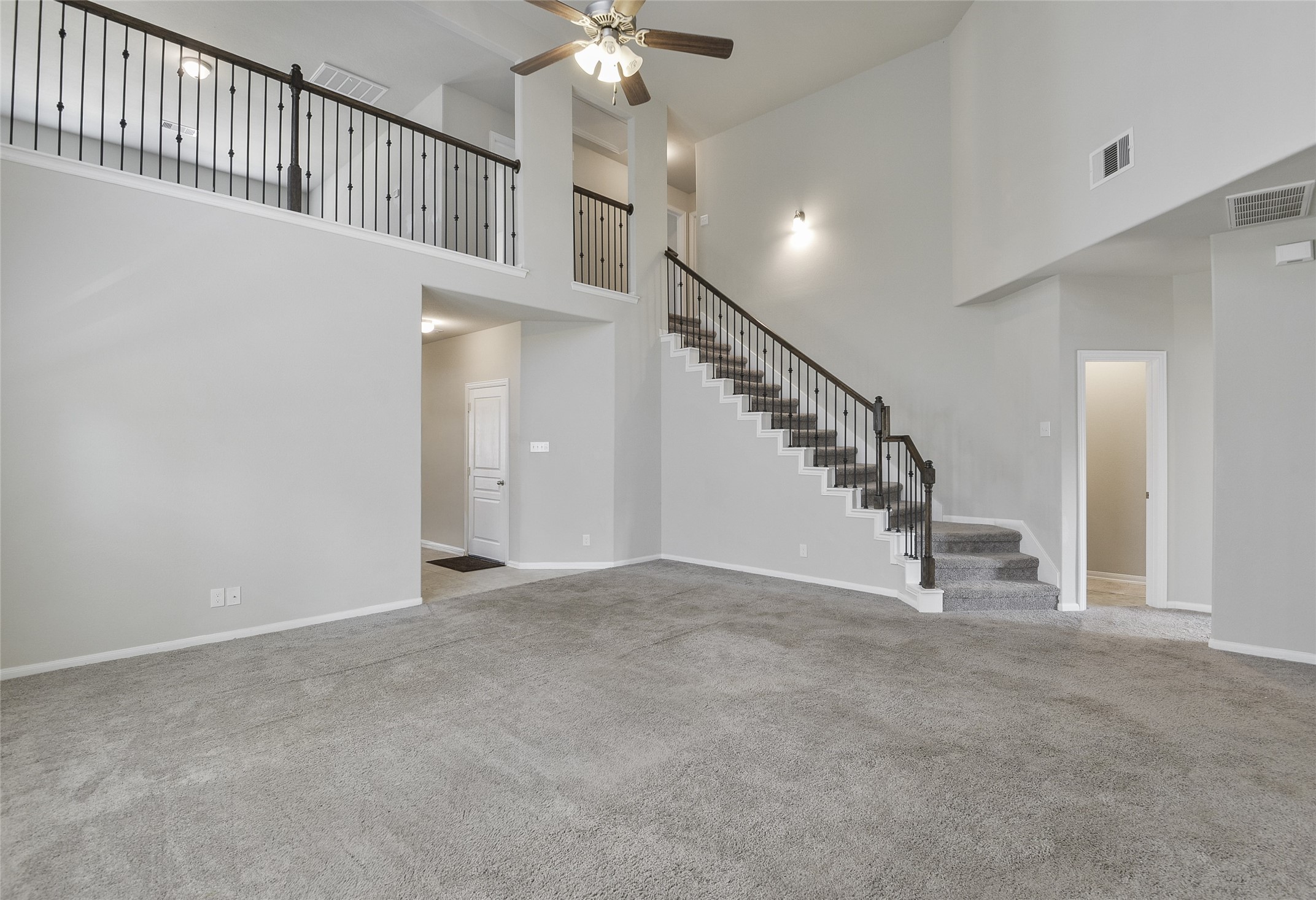 614 Pequin Road Crosby, TX 77532 - Photo 9 of 43 This spacious living area features high ceilings, neutral walls, and carpet flooring. A staircase with a sleek iron railing leads to an upper level, while large windows provide ample natural light. Ideal for a modern, open-concept home.