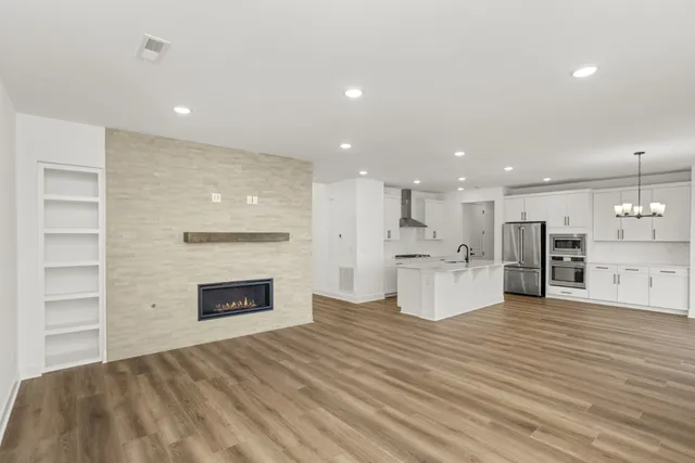 a view of kitchen with kitchen island granite countertop wooden floor stainless steel appliances and cabinets