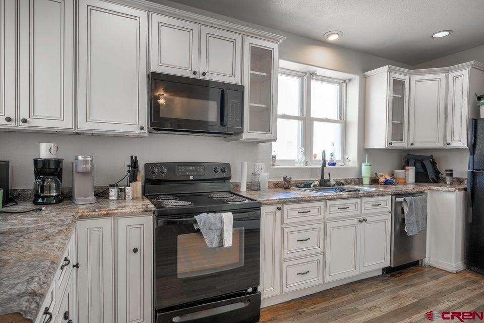 522 East First Street, Unit A & B Trinidad, CO 81082 - Photo 11 of 45 a kitchen with stainless steel appliances granite countertop a stove a sink and white cabinets