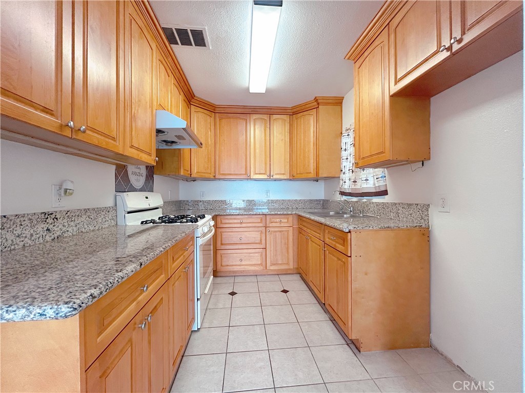 1807 Berkeley Avenue Pomona, CA 91768 - Photo 3 of 8 a kitchen with stainless steel appliances granite countertop a sink counter space cabinets and a large window