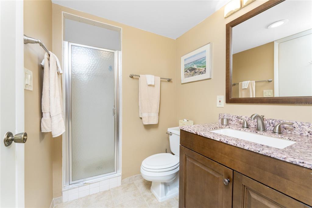 2700 North Beach Road, Unit E107 Englewood, FL 34223 - Photo 28 of 62 a bathroom with a granite countertop toilet sink and a mirror