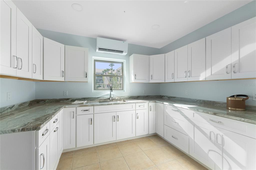 2700 North Beach Road, Unit E107 Englewood, FL 34223 - Photo 61 of 62 a kitchen with granite countertop white cabinets and a sink