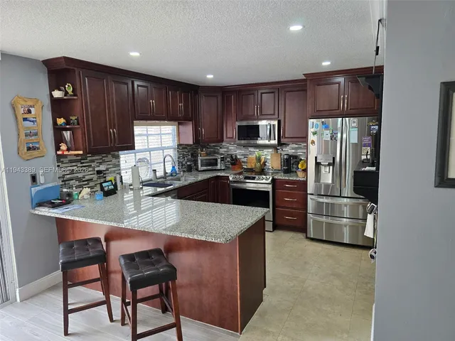 a kitchen with kitchen island granite countertop wooden cabinets a refrigerator a stove a sink and a oven