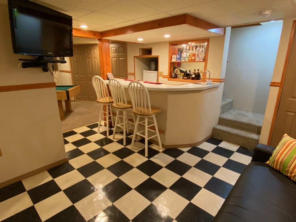 16 Worcester Road Townsend, MA 01469 - Photo 17 of 31 a living room with a black white checkered floor with a gaming machine and dining chairs