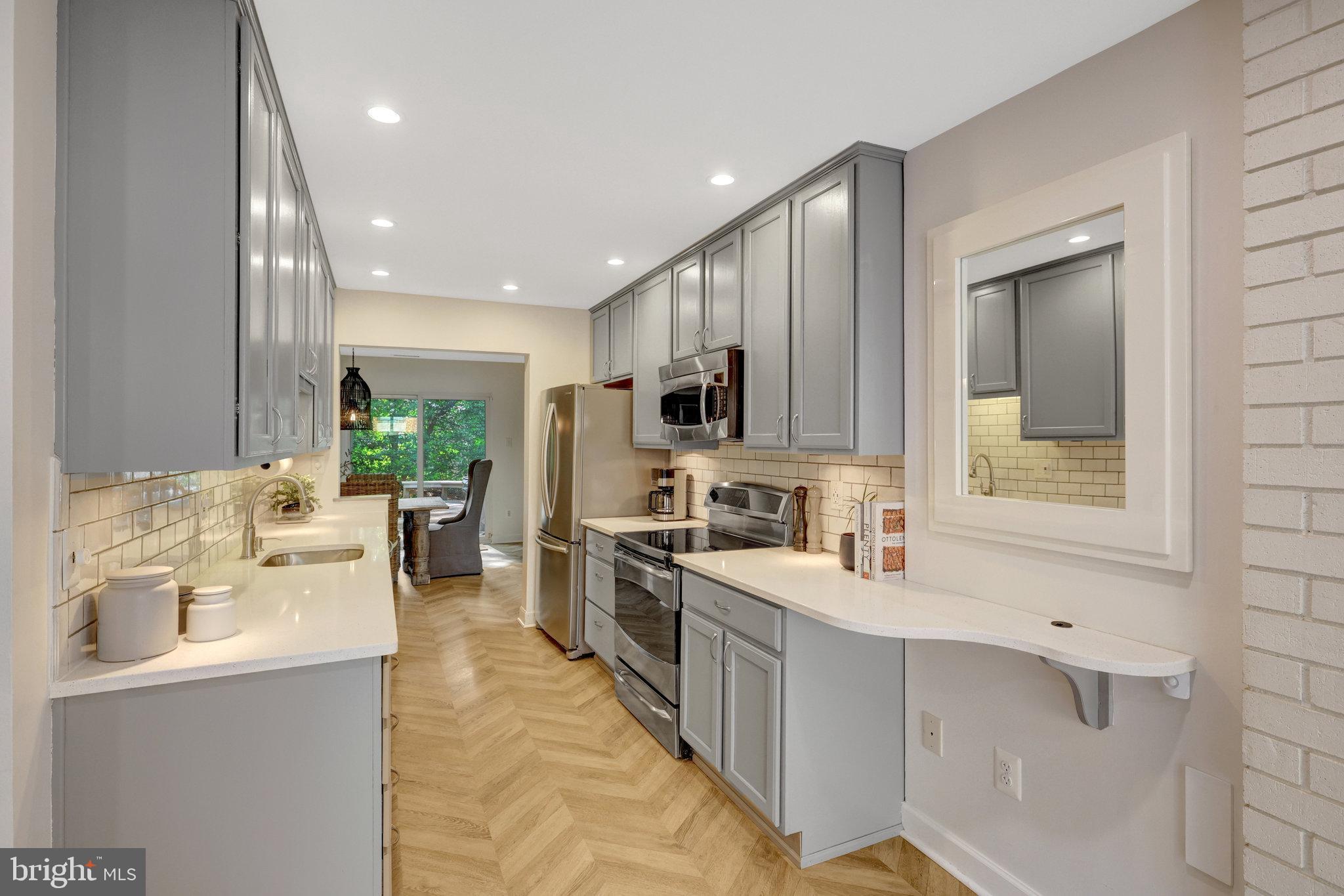 11712 Indian Ridge Road Reston, VA 20191 - Photo 17 of 77 a large white kitchen with kitchen island a large counter top space a sink stainless steel appliances and cabinets