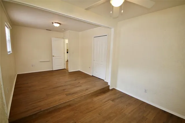 an empty room with a ceiling fan and wooden floor