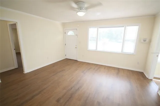 an empty room with wooden floor and windows