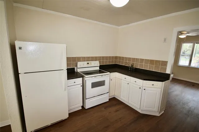 a kitchen with a refrigerator and white cabinets
