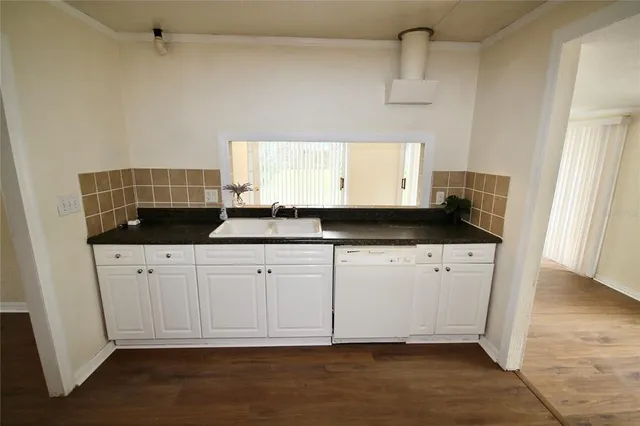 a kitchen with granite countertop white cabinets white appliances and a sink