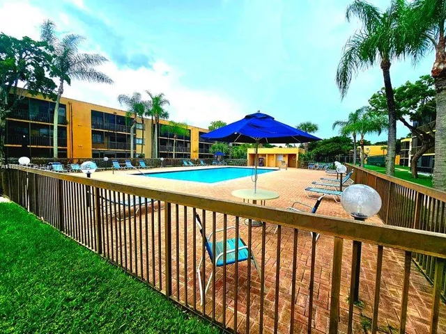 a view of a table and chairs under an umbrella with wooden fence