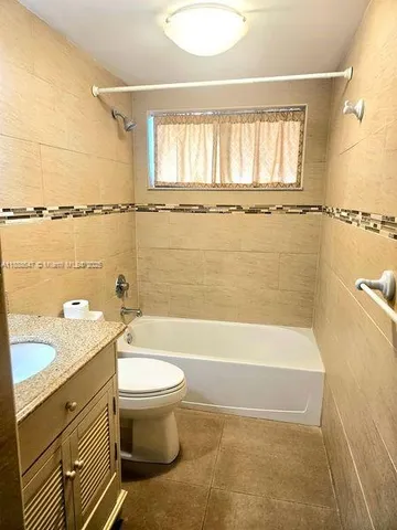 a bathroom with a granite countertop sink a toilet and bathtub