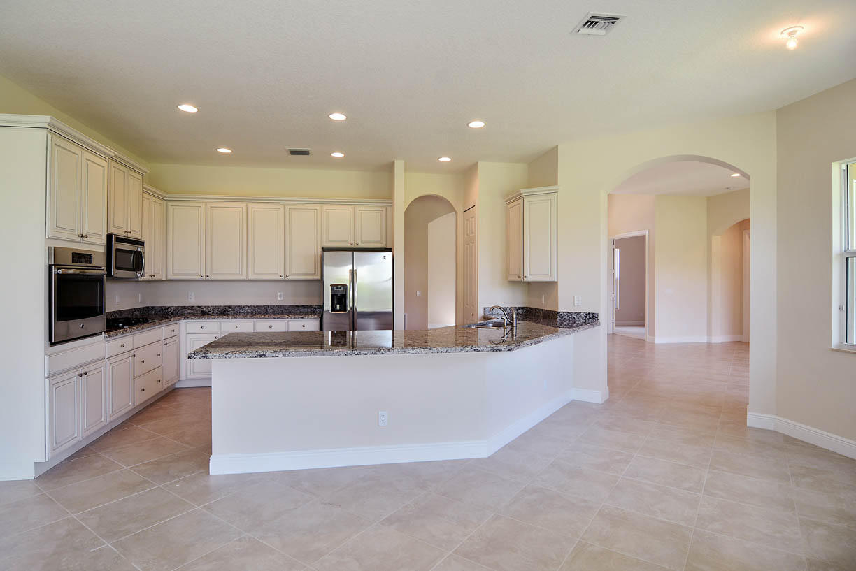 7414 Southeast Ravissant Drive Stuart, FL 34997 - Photo 5 of 25 a large white kitchen with a large counter top and stainless steel appliances