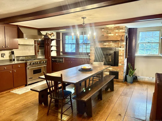 a open kitchen with stainless steel appliances granite countertop a stove a refrigerator a kitchen island a dining table and chairs with wooden floor