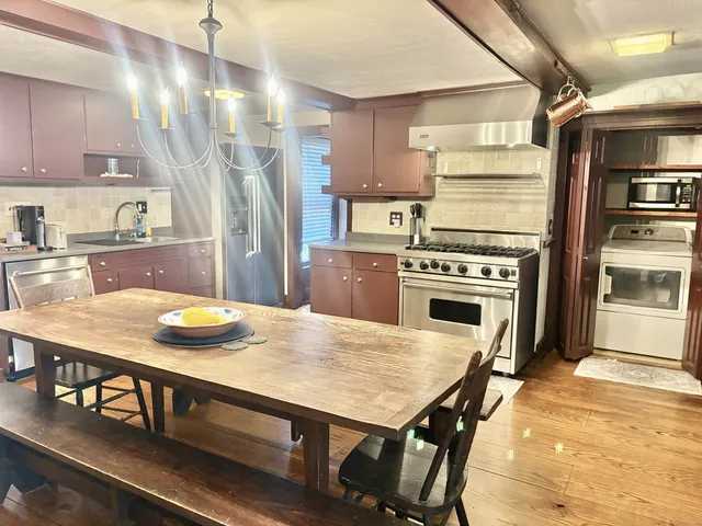 a kitchen with kitchen island a stove a table and chairs in it