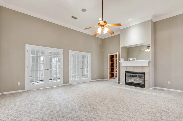an empty room with fireplace chandelier fan and windows