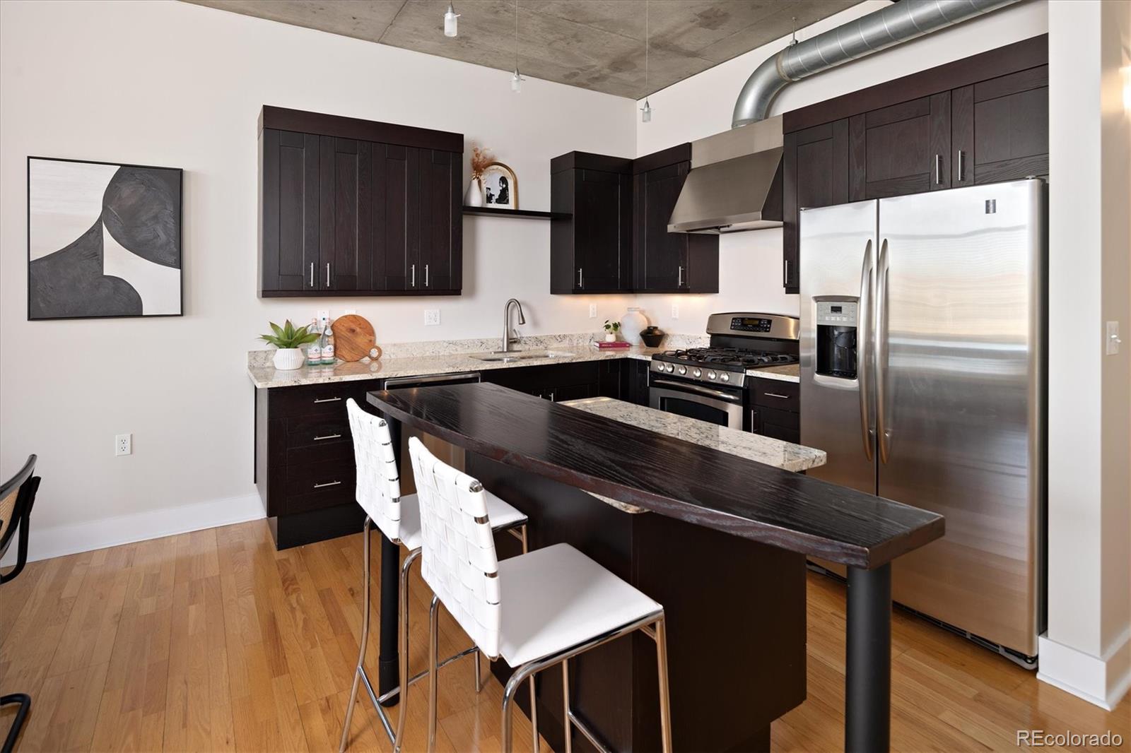 2210 Blake Street, Unit 209 Denver, CO 80205 - Photo 15 of 33 a kitchen with a sink a kitchen island and stainless steel appliances