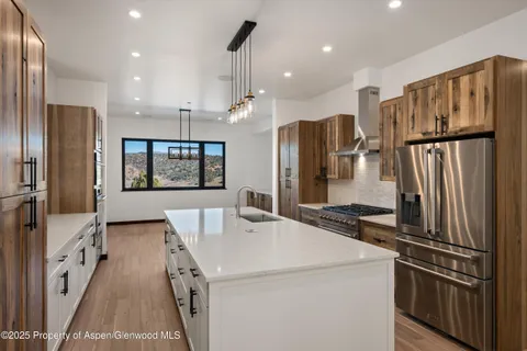 a large white kitchen with a large window a refrigerator and a sink