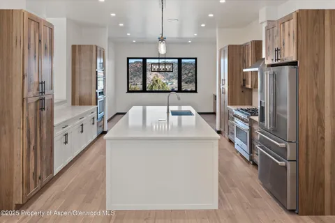 a kitchen with stainless steel appliances granite countertop a sink a stove and a refrigerator