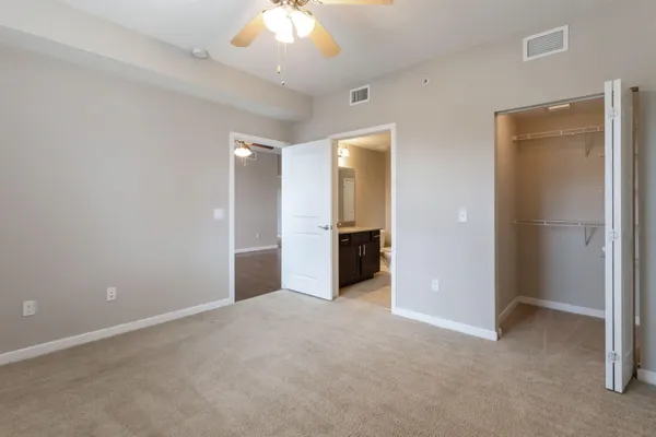 an empty room with kitchen view and a chandelier fan