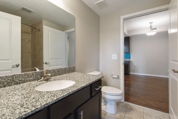 a bathroom with a granite countertop sink toilet a mirror and shower