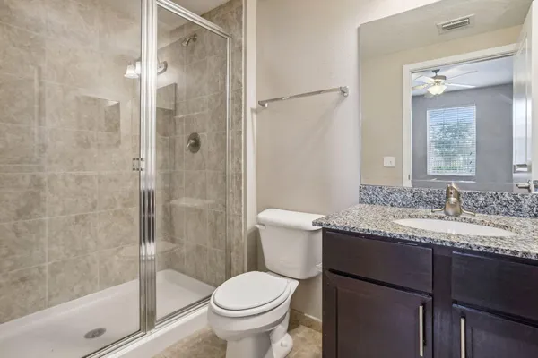 a bathroom with a granite countertop sink toilet and shower