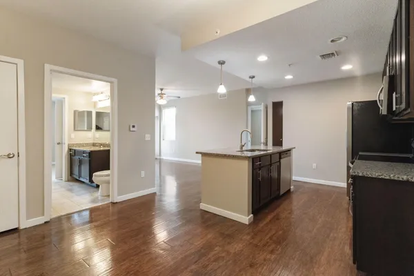 a large kitchen with stainless steel appliances a large counter top and a refrigerator